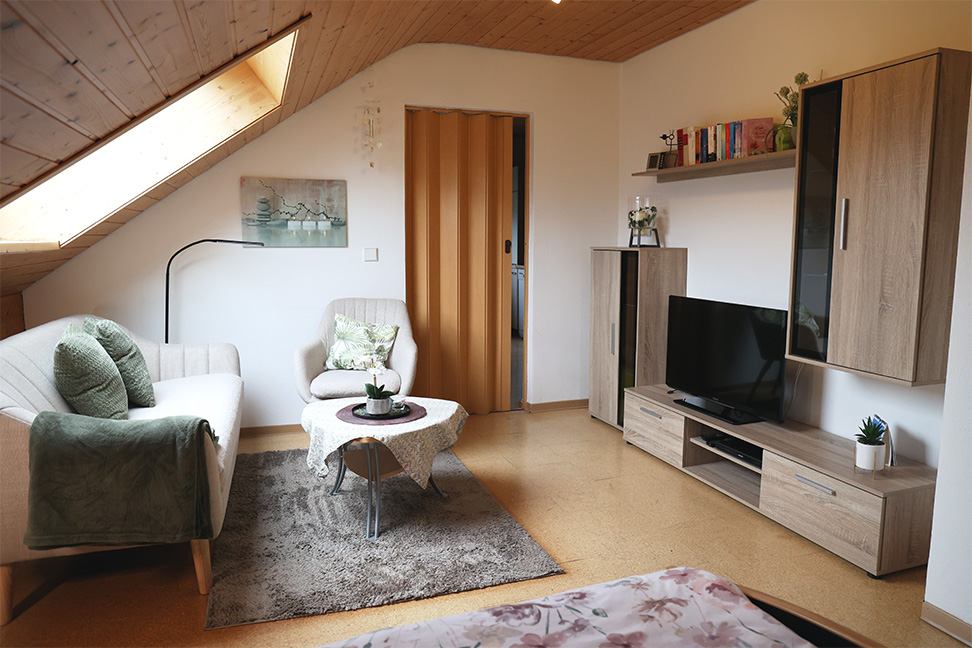 Wohnzimmer mit einer Schrankwand, Fernseher, Sessel und Couchtisch